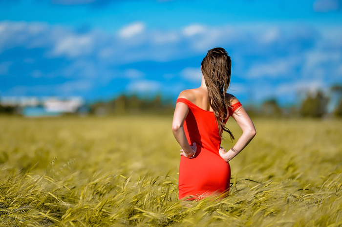 Woman wearing red dress standing in rye field