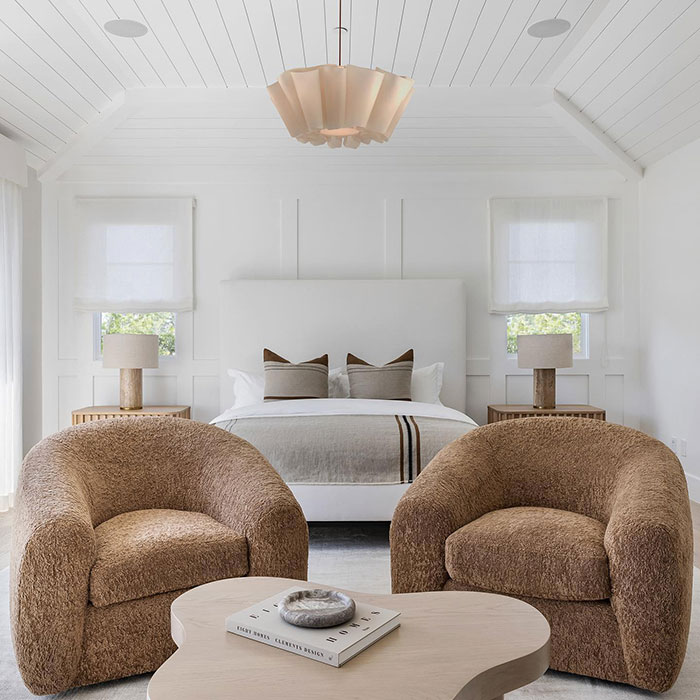 White master bedroom with brown chairs beside