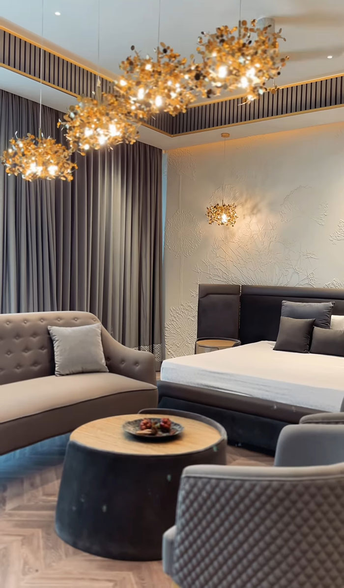 Modern maximalist master bedroom featuring elegant lighting, plush seating, textured wall, and luxurious neutral décor. Modern maximalist master bedroom featuring elegant lighting, plush seating, textured wall, and luxurious neutral décor.