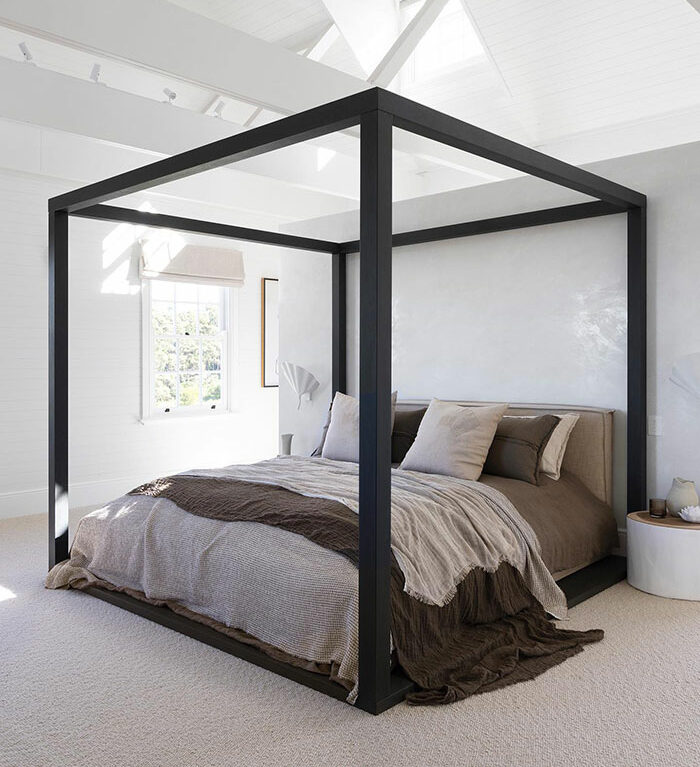 Black canopy bed in a bright white master bedroom