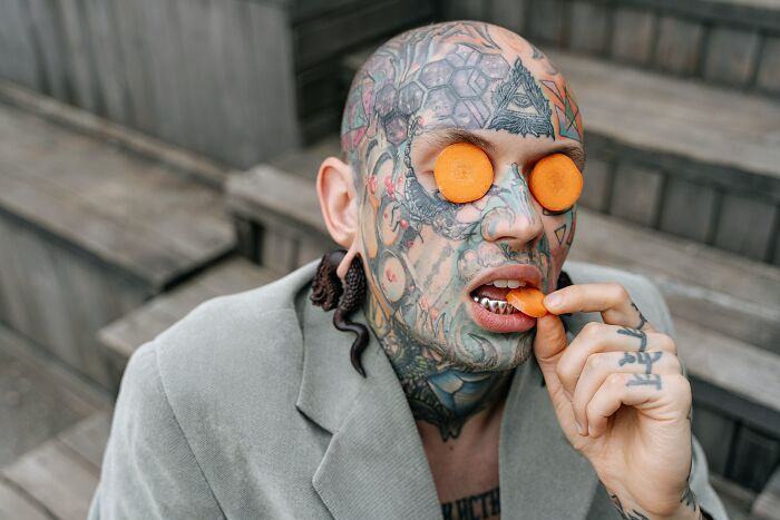Tattooed Man Eating A Carrot 