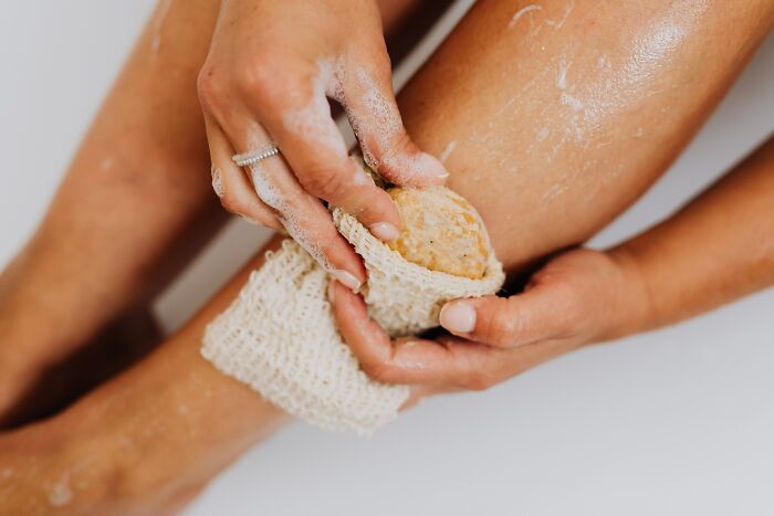 Woman Using Loofah To Scrub Her Legs 