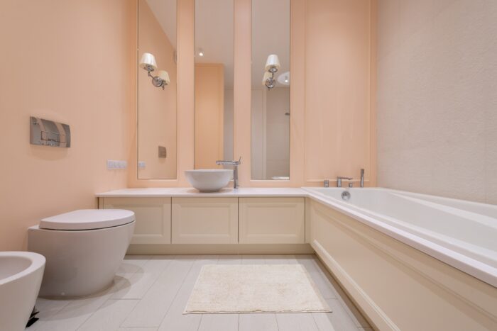 Bathroom with light pink wallpaper and sink with toilet