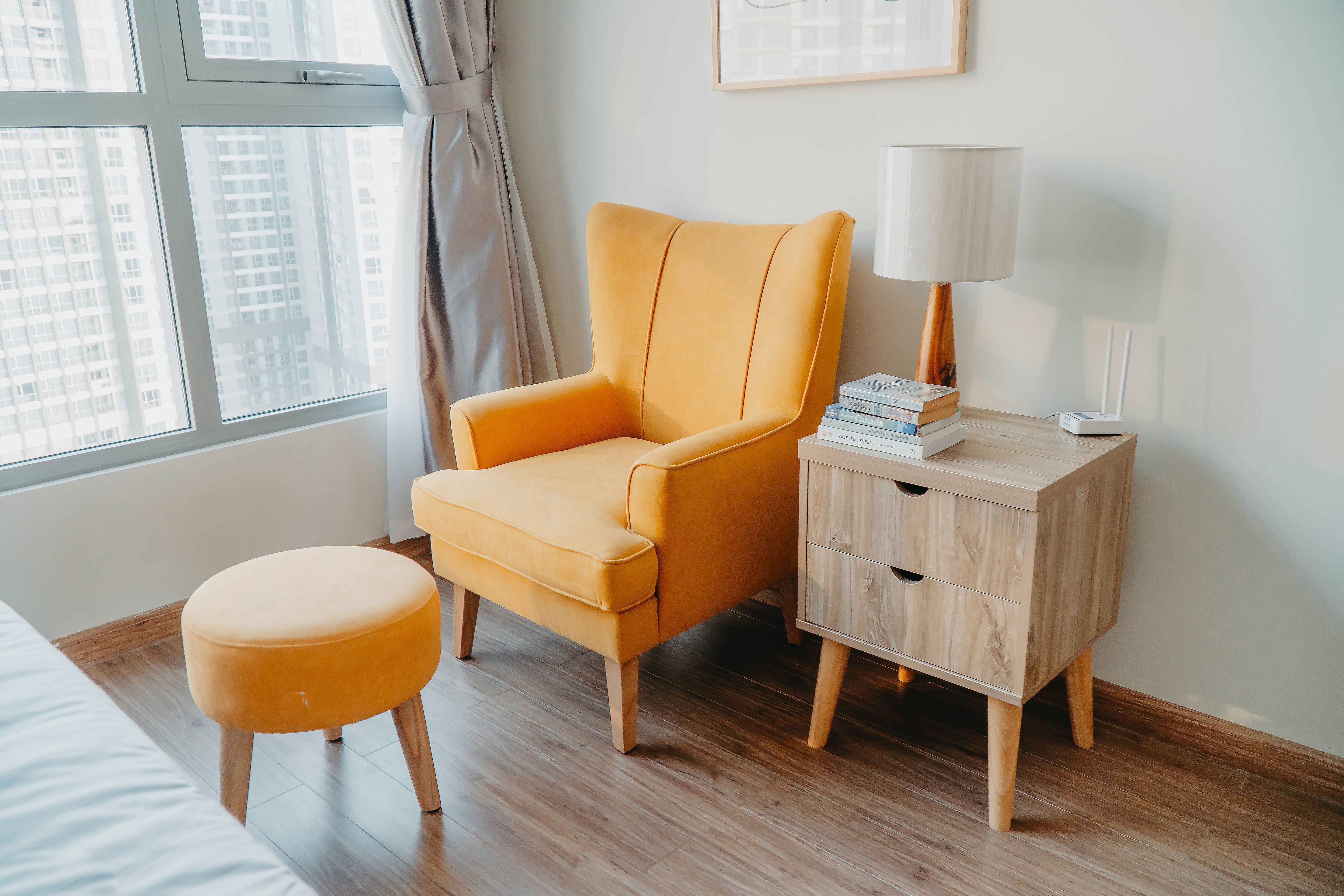 yellow armchair and ottoman beside wooden nightstand by the wall