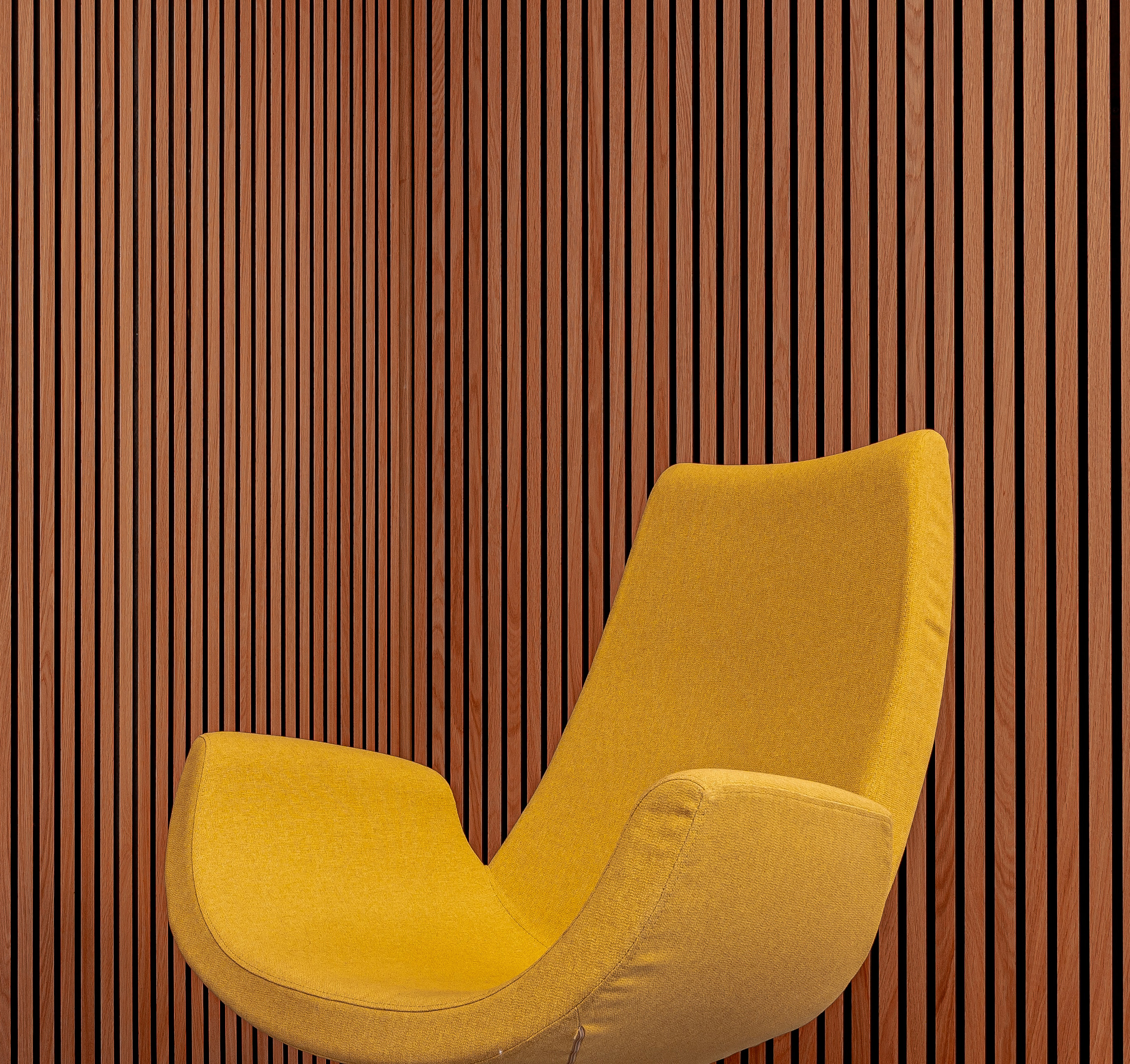 a yellow chair sitting in front of a wooden wall