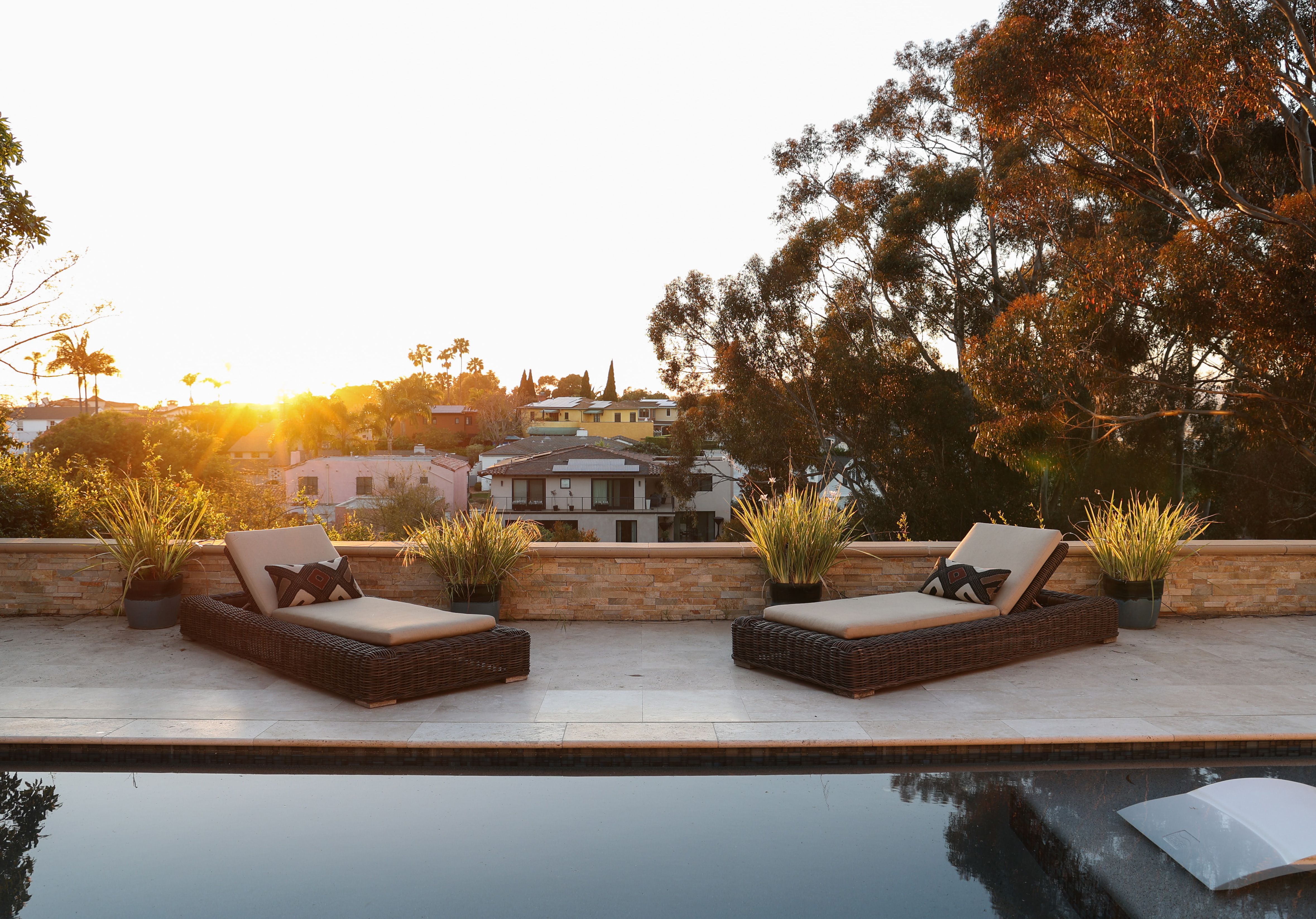 a pool with two lounge chairs and a view of a house