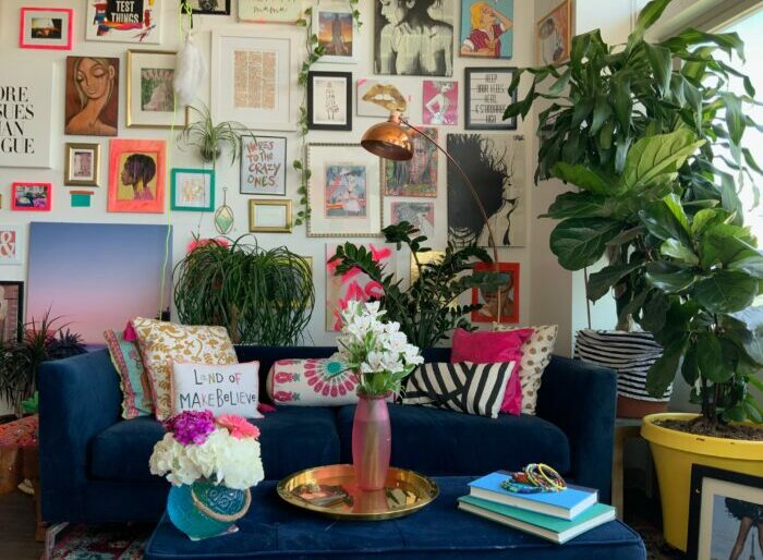 a maximalist living room with a blue couch and vases with flowers
