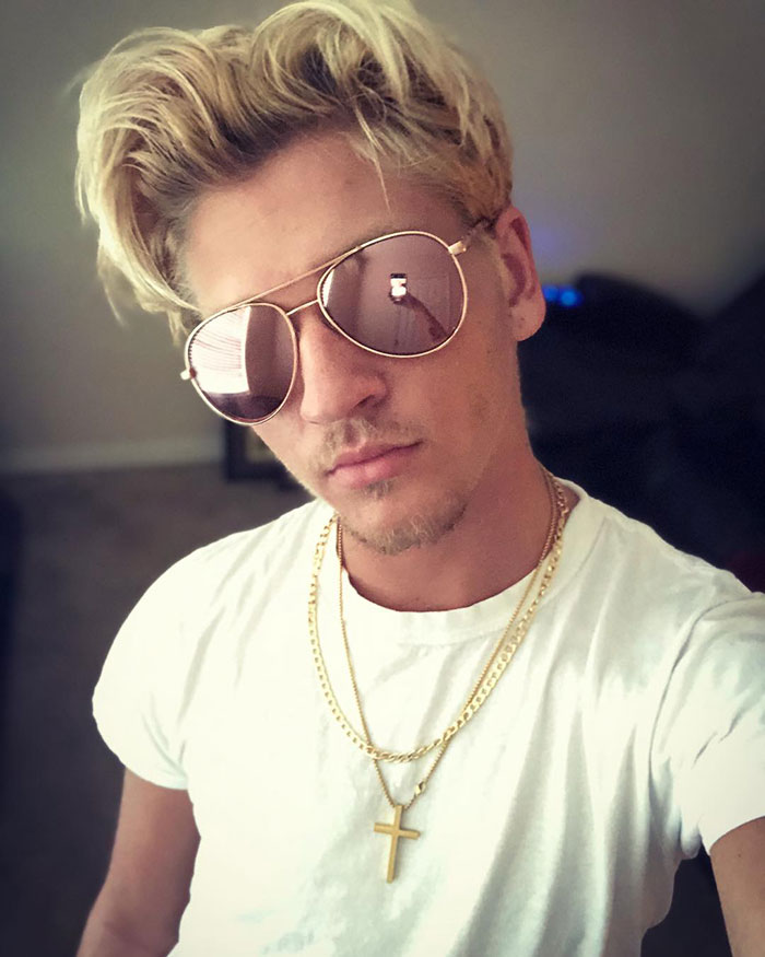 TikToker Ethan in sunglasses and white shirt, showcasing viral style linked to trolling bullies by getting tattoos. TikToker Ethan in sunglasses and white shirt, showcasing viral style linked to trolling bullies by getting tattoos.