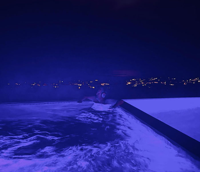 Man in a pool at night, surrounded by city lights, creating a mysterious atmosphere with Batman references. Man in a pool at night, surrounded by city lights, creating a mysterious atmosphere with Batman references.