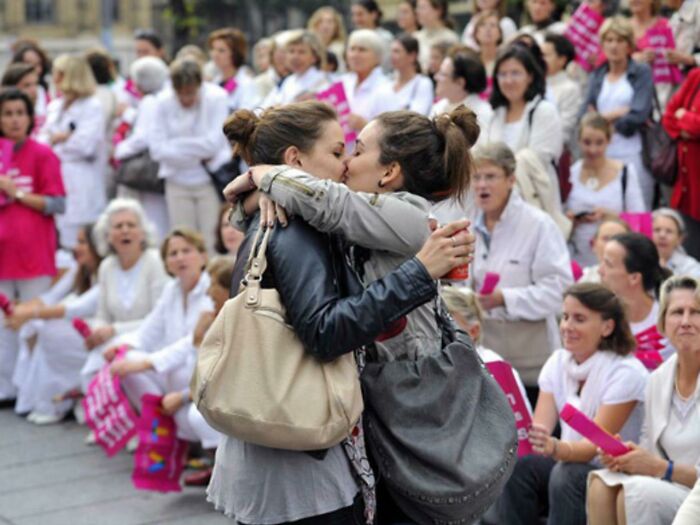 Dos chicas besándose frente a una protesta anti-gay