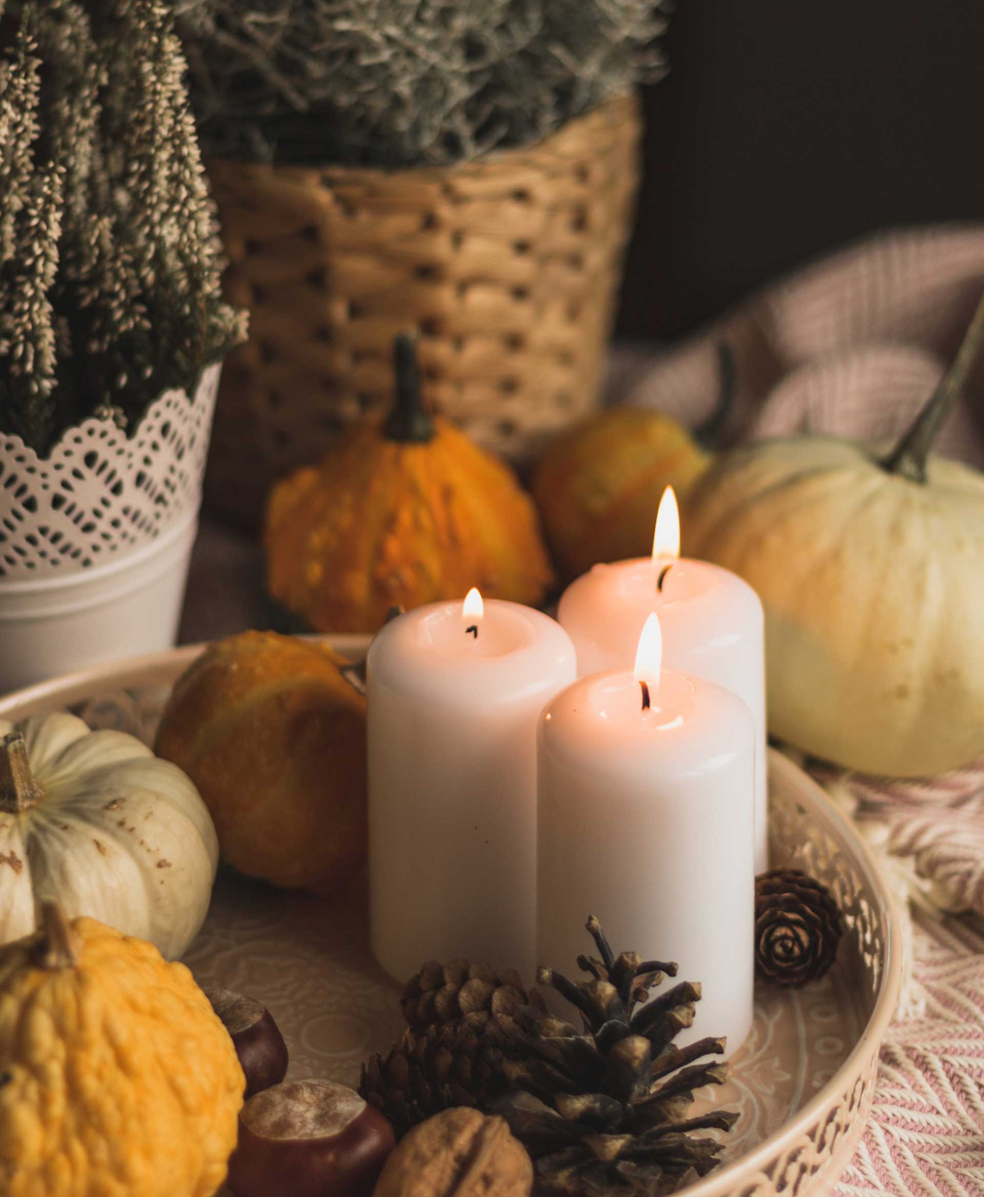 Three lighted candles and small decorative pumpkins on the table 