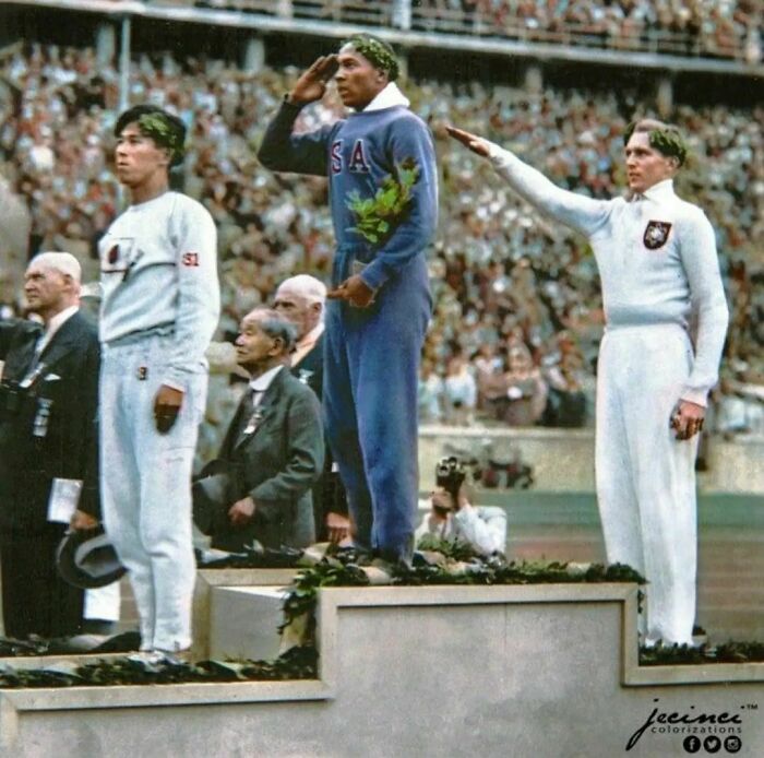 El atleta estadounidense Jesse Owens saluda tras recibir su medalla de oro en salto tras derrotar al atleta de la Alemania nazi Lutz Long en las Olimpiadas de Berlín de 1936