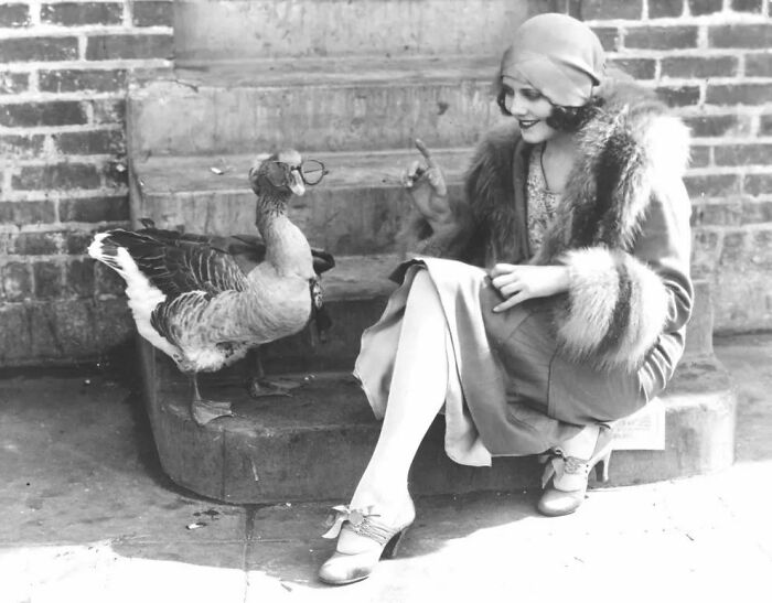 La actriz Fay Webb con su ganso mascota al que han puesto gafas, 1925