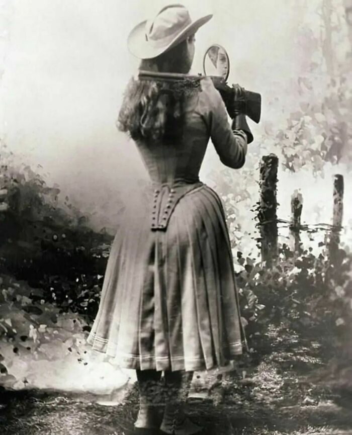 La tiradora Annie Oakley disparando sobre su hombro con ayuda de un espejo, 1899