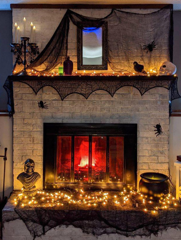 Fireplace decorated with black spider webs and warm fairy lights