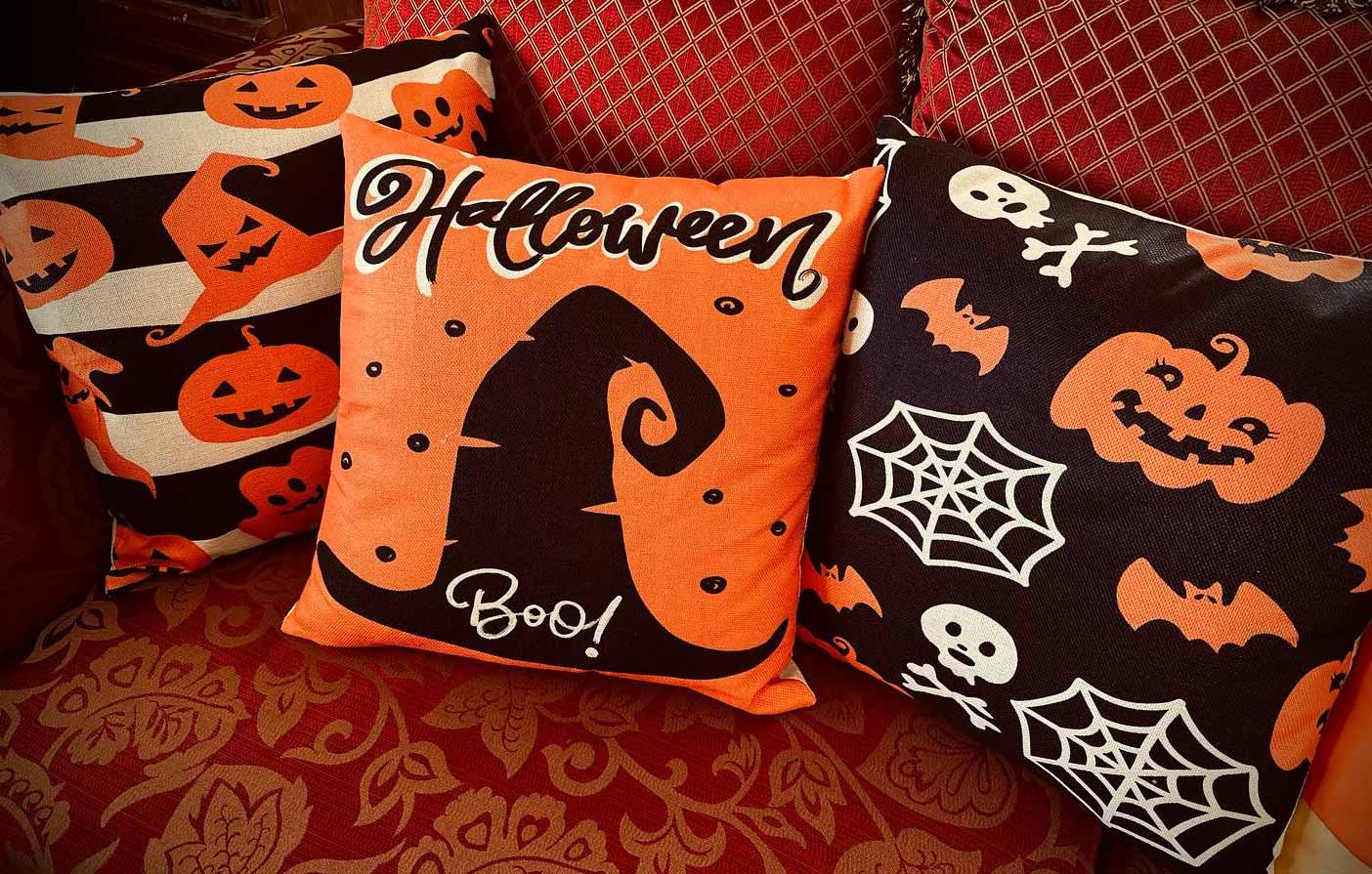 Three Halloween themed pillows in orange, black and white colors