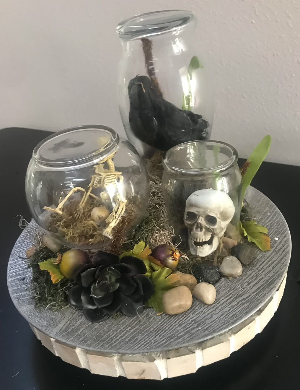 Three Halloween terrariums with raven, skeleton and skull inside