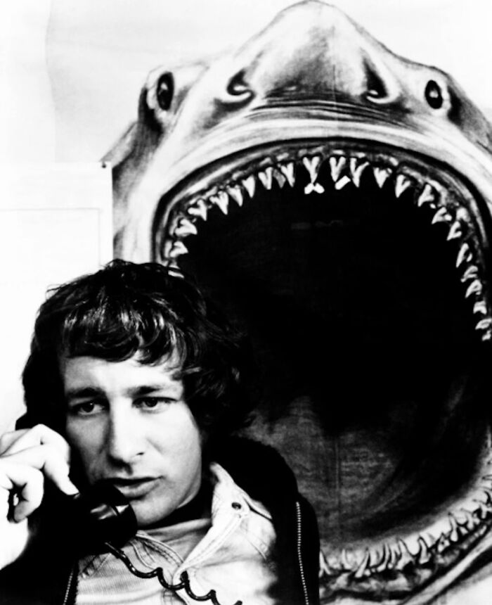 Steven Spielberg Making A Call With The Shark From Jaws Behind Him