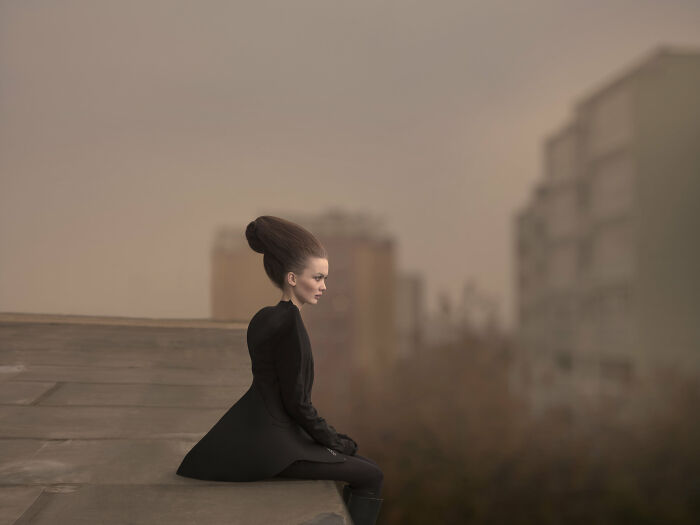 An image of a woman sitting at the edge of the roof