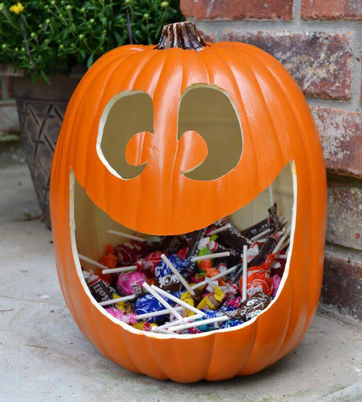 Faux pumpkin candy holder with many candies