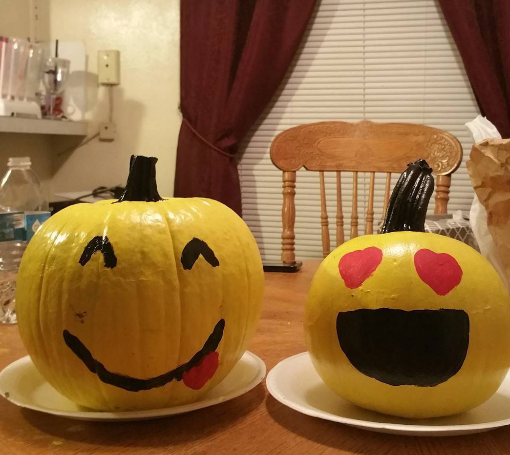 Two painted pumpkin emojis on a table