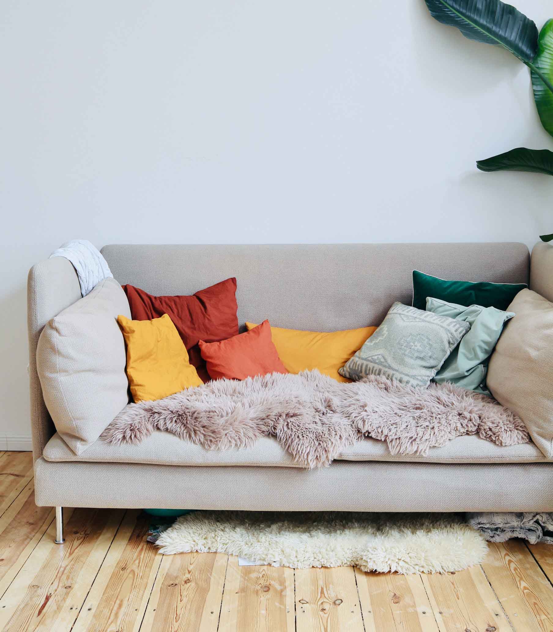 A light sofa with colorful pillows and a soft rug on it
