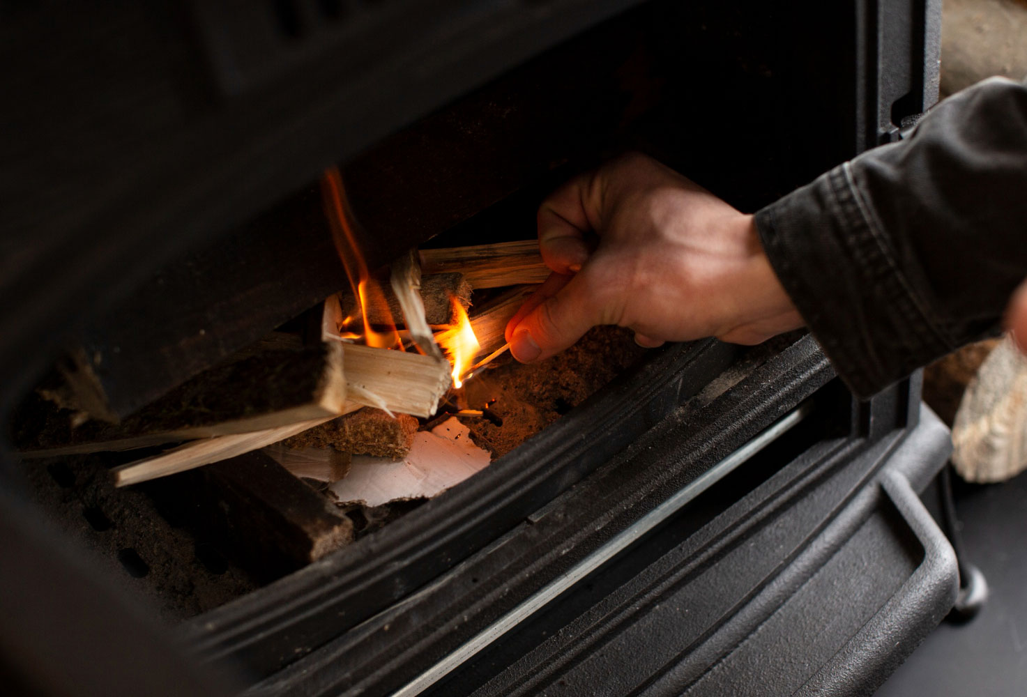 Person starting a fire in a wood-burning stove