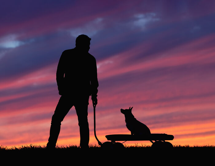 Colorful sunset sky and the dog wit his owner