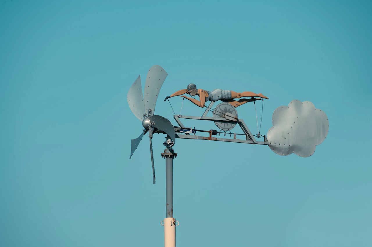 Wind swimmer weather vane under blue sky