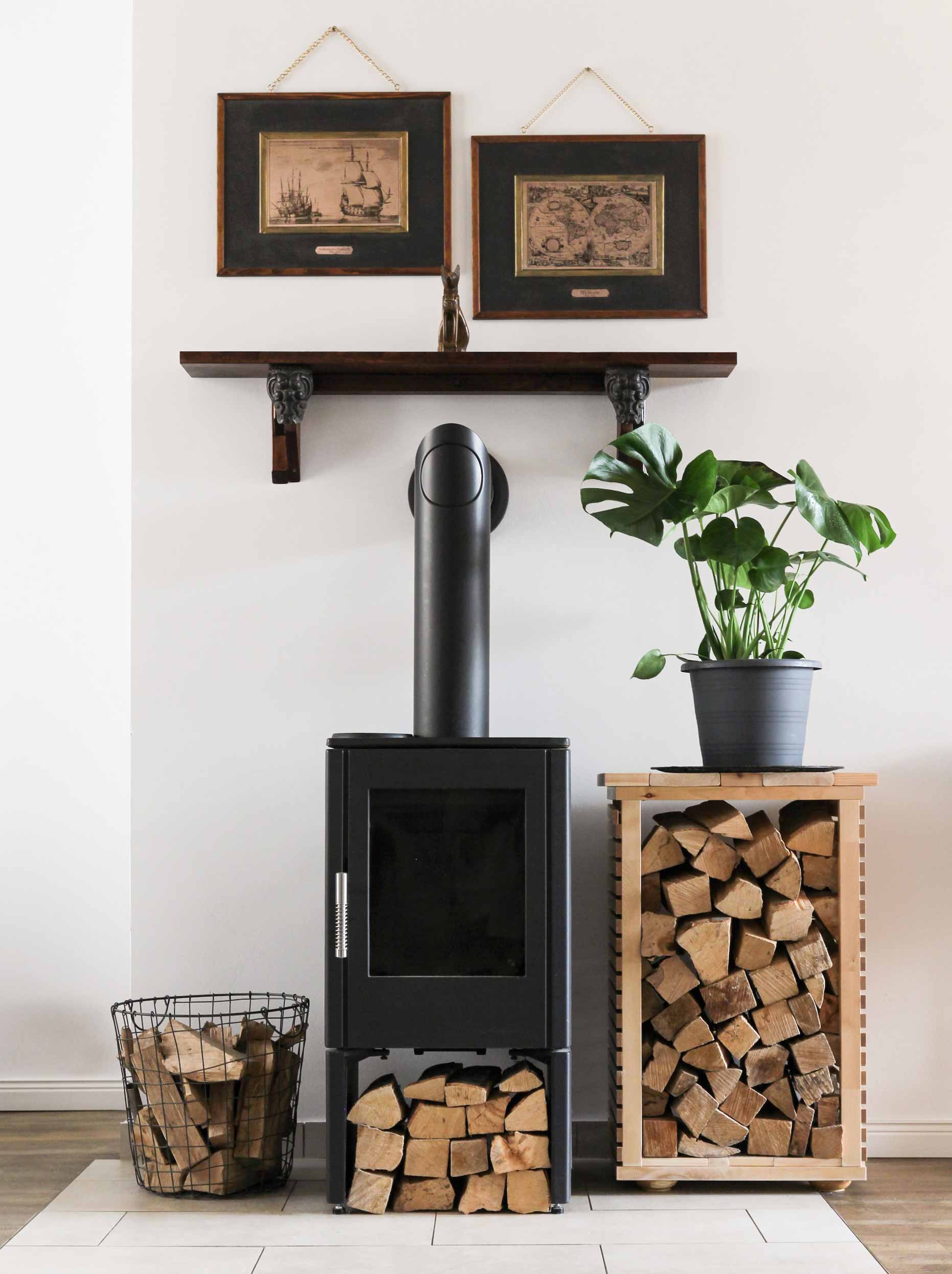 Wood-burning stove, wood neatly placed near it, and a plant