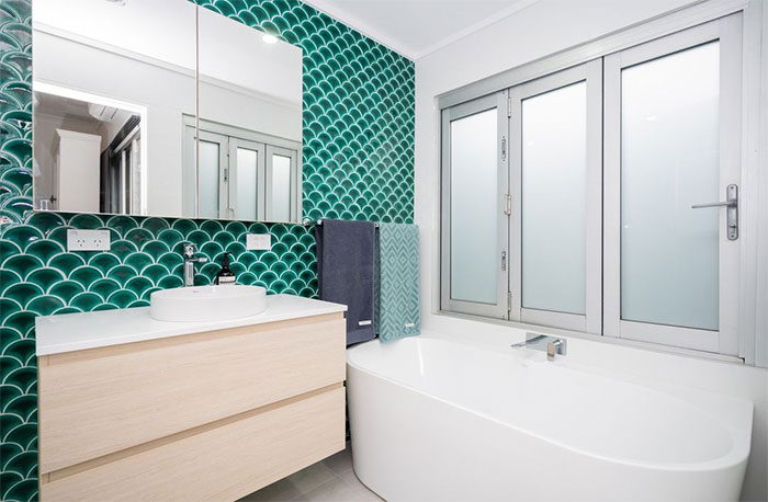 bathroom with green fish-scale wall and sink