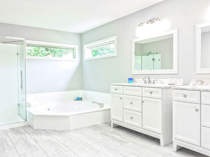all-white ceramic bathtub near white wooden vanity sink