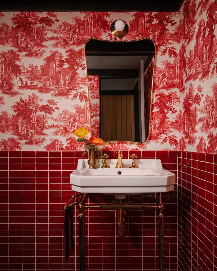 red bathroom with red rectangular tiles and floral wallpaper