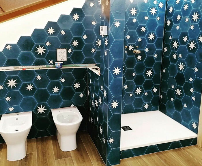 Bathroom featuring blue hexagon bathroom tile design with white star patterns on walls surrounding shower and fixtures. Bathroom featuring blue hexagon bathroom tile design with white star patterns on walls surrounding shower and fixtures.