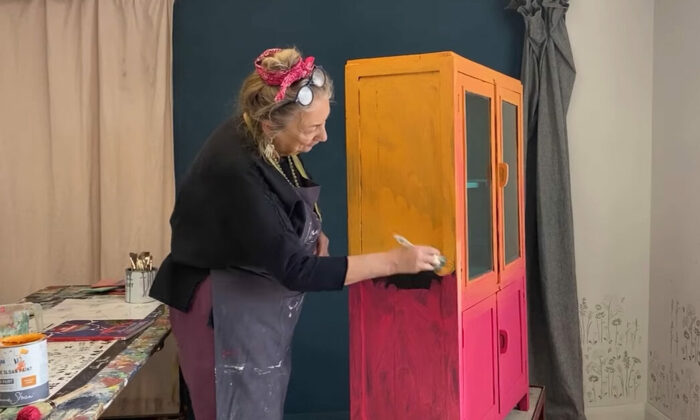 Annie Sloan painting a cupboard with red chalk paint