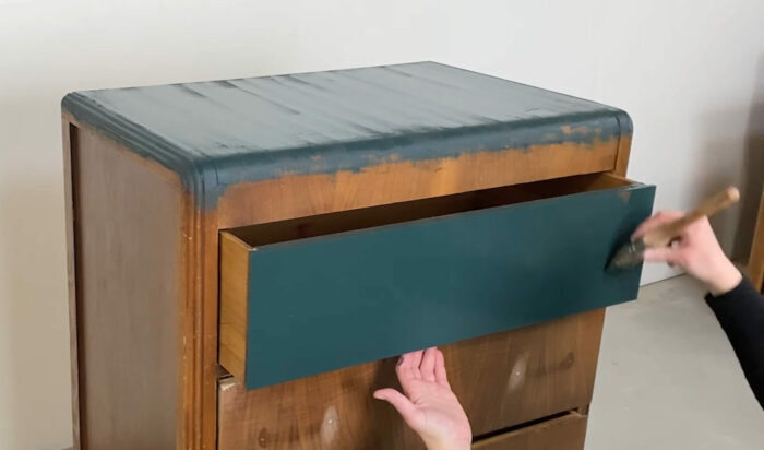 Person painting a cupboard blue with chalk paint