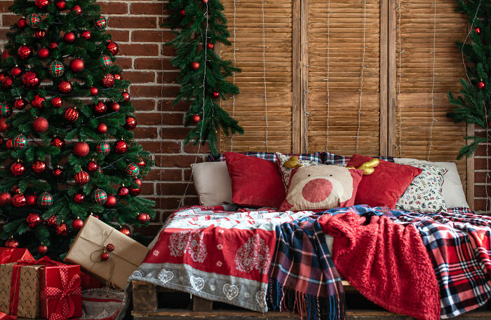 Big bed with covers and pillows near christmas tree