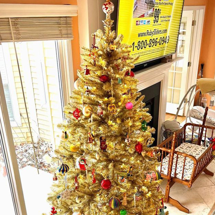 Golden Christmas tree next to a fireplace 