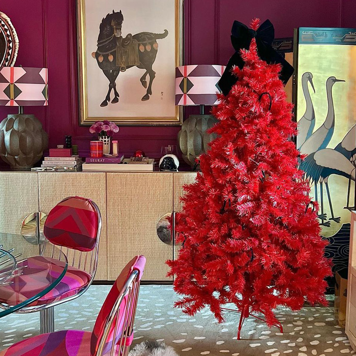Red Christmas tree with a black bow on the top of it 