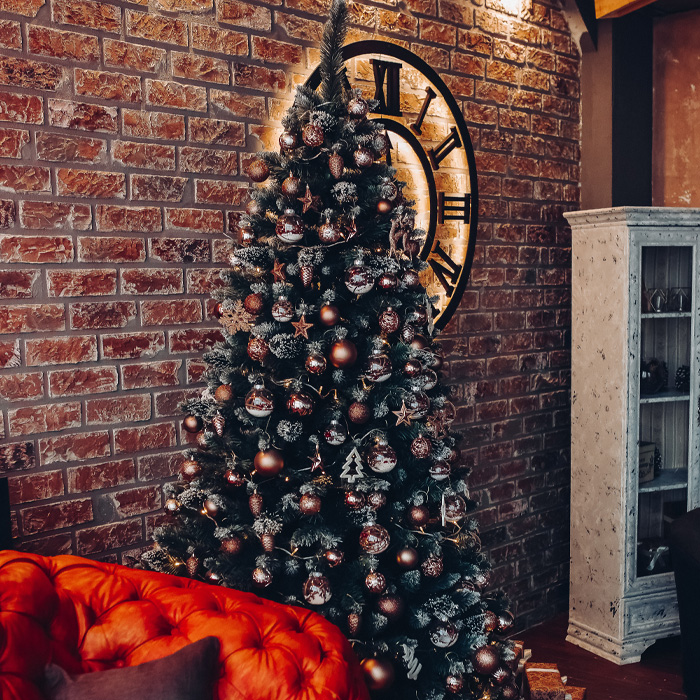 Decorated Christmas tree next to a brick wall and a red sofa