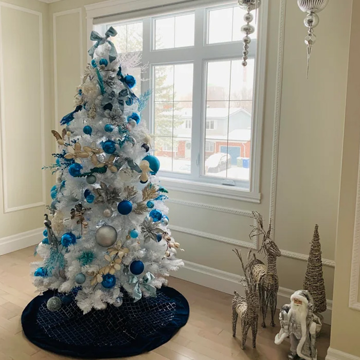 White Christmas tree decorated by blue ornaments 
