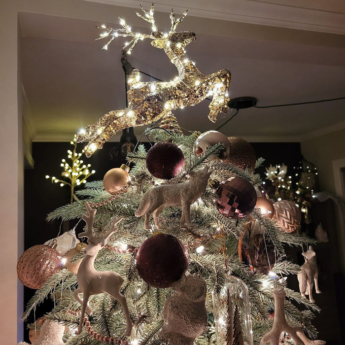 A lighted reindeer as a topper on a Christmas tree 