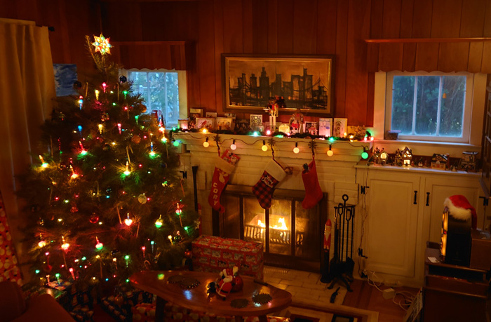 Decorated Christmas tree next to a fireplace with the stockings 