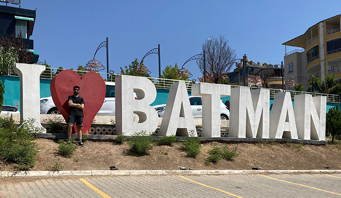Man posing near a Batman, Turkey city sign 