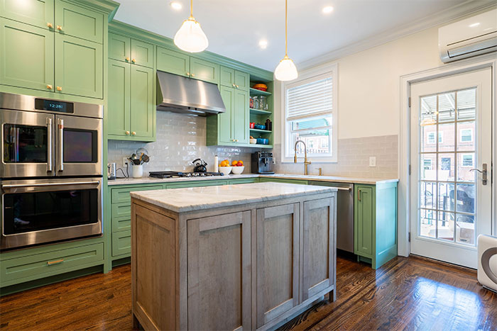 Country kitchen with green cupboards and gray table