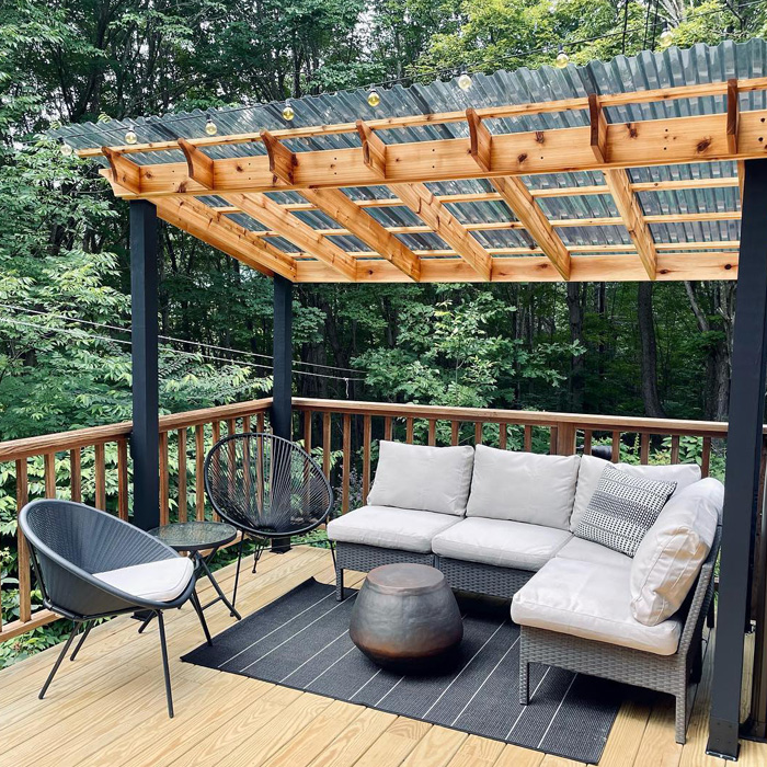 Backyard deck with covered pergola and grey furniture creating a creative outdoor seating area surrounded by trees Backyard deck with covered pergola and grey furniture creating a creative outdoor seating area surrounded by trees