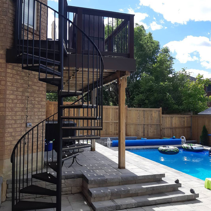 Spiral staircase deck design next to swimming pool in backyard showcasing creative backyard deck ideas outdoors. Spiral staircase deck design next to swimming pool in backyard showcasing creative backyard deck ideas outdoors.
