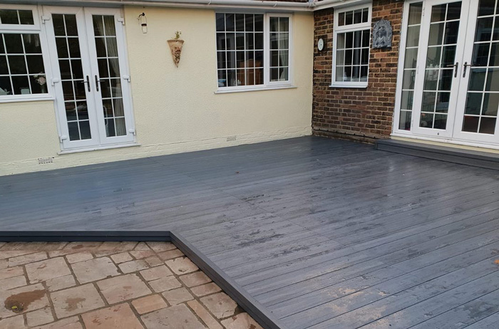 Composite backyard deck area with creative design, enhancing outdoor living space next to brick and cream house walls. Composite backyard deck area with creative design, enhancing outdoor living space next to brick and cream house walls.