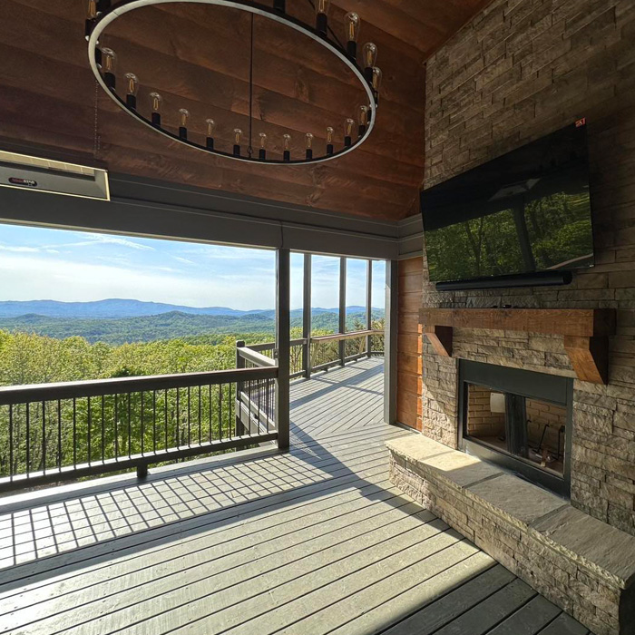 Deck with TV mounted above fireplace overlooking wooded landscape, showcasing creative backyard deck ideas for outdoor enjoyment. Deck with TV mounted above fireplace overlooking wooded landscape, showcasing creative backyard deck ideas for outdoor enjoyment.
