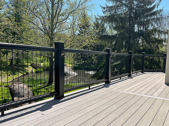Classic black deck railing on a wooden porch overlooking a lush green landscape with trees and a small stream Classic black deck railing on a wooden porch overlooking a lush green landscape with trees and a small stream